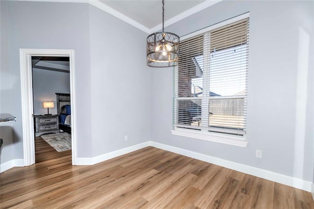 unfurnished dining area with hardwood / wood-style flooring, ornamental molding, and a notable chandelier