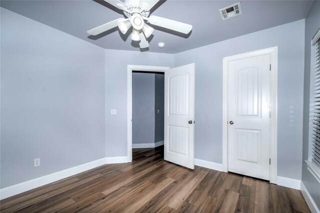 unfurnished bedroom with ceiling fan and dark wood-type flooring