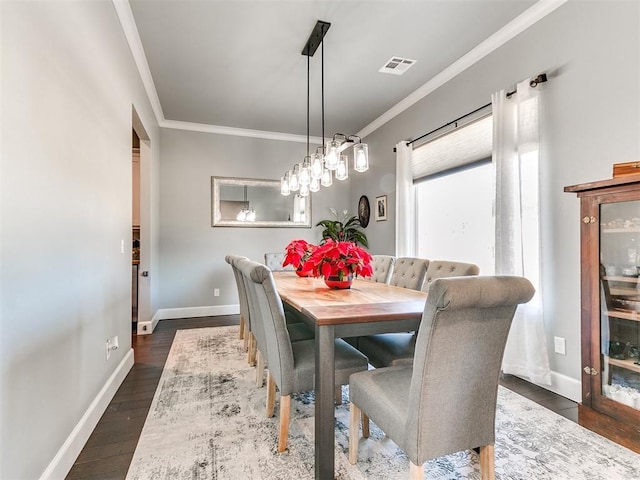 dining room with baseboards, visible vents, dark wood finished floors, and ornamental molding