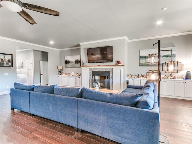 living area featuring crown molding, dark wood-style flooring, a fireplace, and baseboards