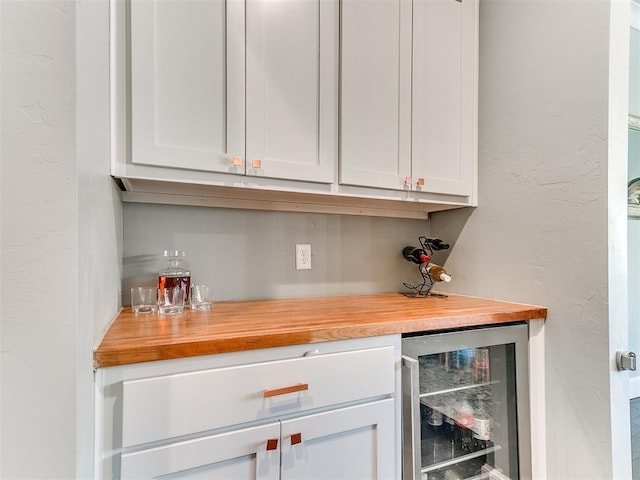 bar with beverage cooler, a textured wall, and a bar