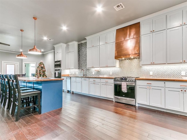 kitchen featuring a center island, decorative light fixtures, custom range hood, appliances with stainless steel finishes, and white cabinetry