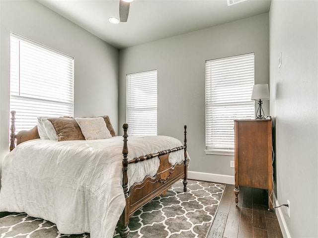 bedroom with multiple windows, dark wood-style flooring, a ceiling fan, and baseboards