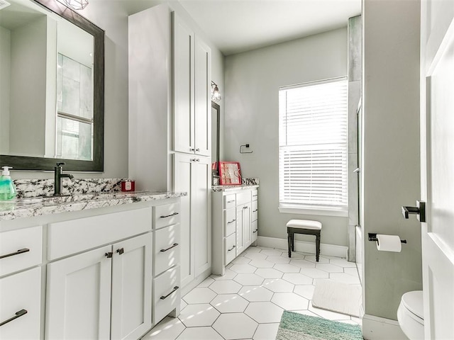 full bath with toilet, tile patterned flooring, baseboards, and vanity