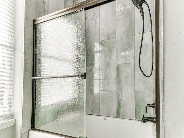 bathroom featuring combined bath / shower with glass door