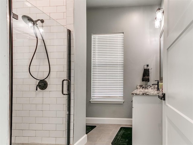 bathroom featuring a stall shower, tile patterned flooring, vanity, and baseboards