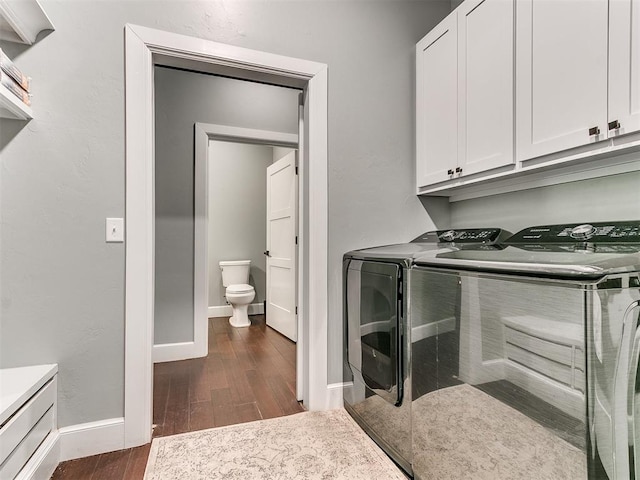 laundry room featuring cabinet space, washing machine and dryer, baseboards, and dark wood-type flooring