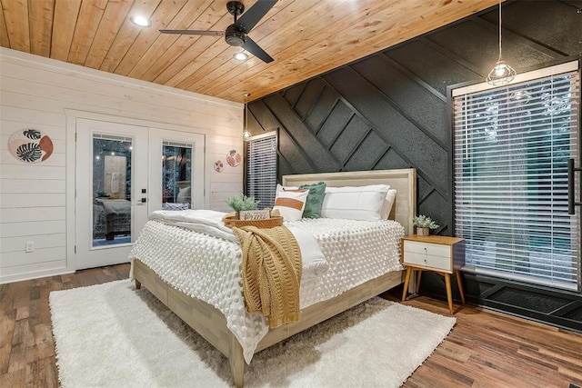 bedroom with ceiling fan, hardwood / wood-style floors, and wood walls