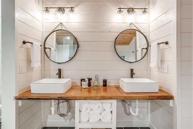 bathroom with dual sinks and wood walls