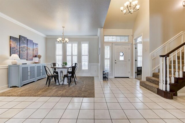 tiled foyer entrance featuring a chandelier, ornamental molding, and a healthy amount of sunlight