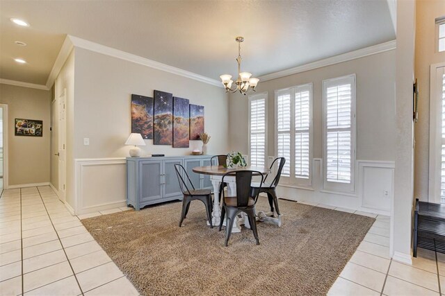 dining area featuring a notable chandelier, ornamental molding, and light tile patterned floors