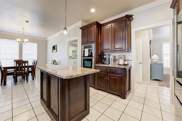 kitchen with pendant lighting, stainless steel double oven, dark brown cabinetry, and washing machine and clothes dryer