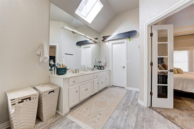 bathroom with wood-type flooring, vanity, and lofted ceiling with skylight