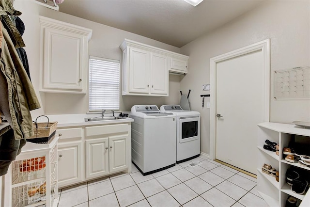 laundry area with cabinets, light tile patterned floors, washing machine and clothes dryer, and sink