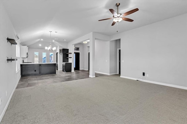 unfurnished living room featuring ceiling fan with notable chandelier, light carpet, and vaulted ceiling