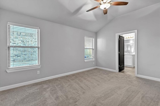 carpeted empty room with a wealth of natural light, lofted ceiling, and ceiling fan