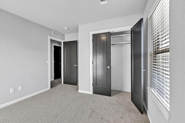 unfurnished bedroom featuring light colored carpet and a closet