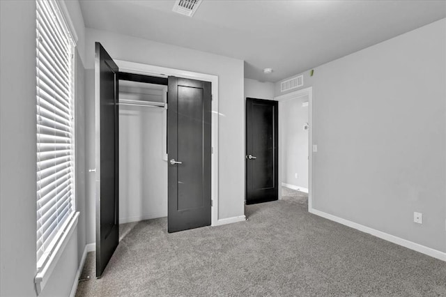 unfurnished bedroom featuring multiple windows, light colored carpet, and a closet