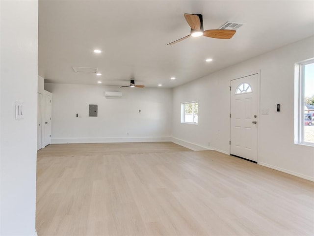 interior space featuring an AC wall unit, electric panel, ceiling fan, and light hardwood / wood-style floors