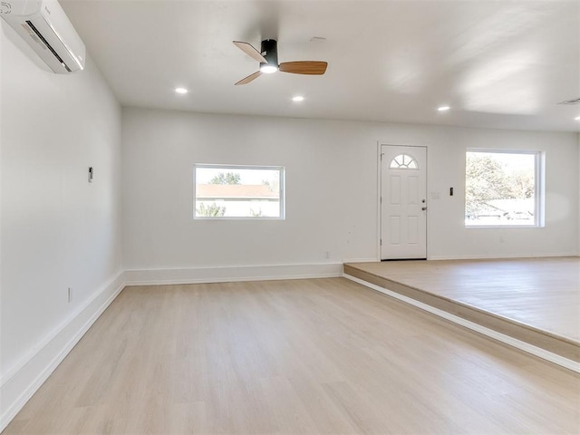 entryway with a wall unit AC, ceiling fan, and light hardwood / wood-style flooring