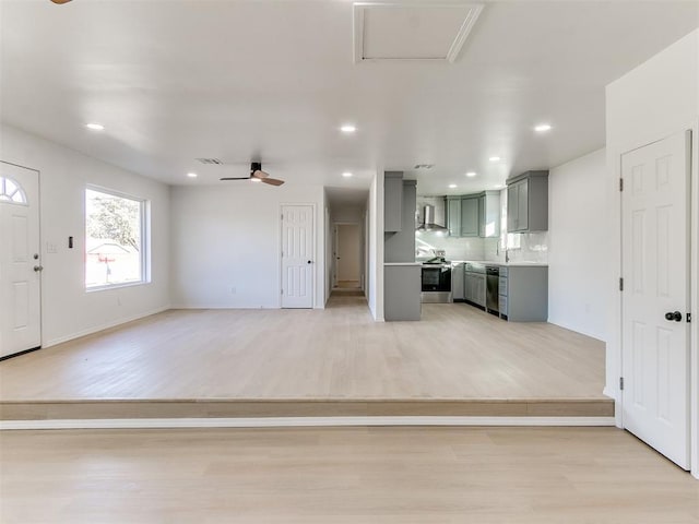 unfurnished living room featuring light wood-type flooring, ceiling fan, and sink