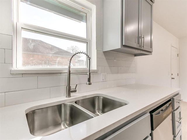 kitchen featuring backsplash, gray cabinetry, dishwasher, and sink