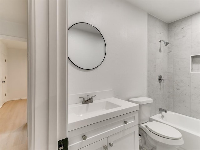 full bathroom with hardwood / wood-style floors, vanity, toilet, and tiled shower / bath