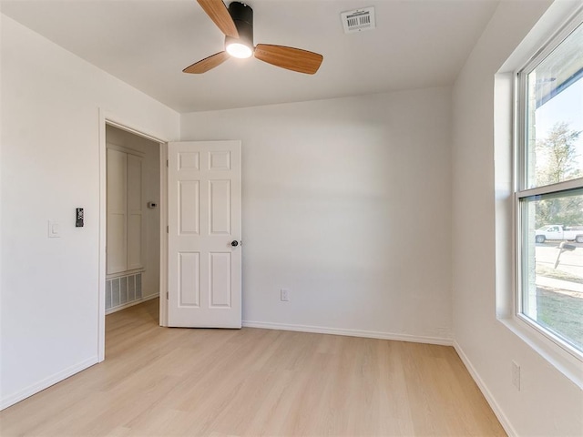 spare room featuring a wealth of natural light, ceiling fan, and light wood-type flooring