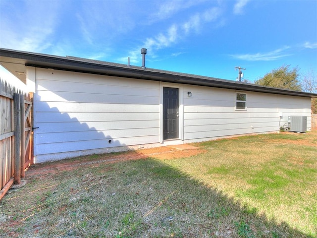 rear view of property featuring a yard and central AC unit