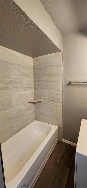 bathroom with tiled shower / bath combo, wood-type flooring, and a textured ceiling