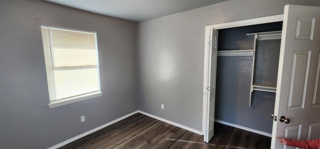 unfurnished bedroom with dark hardwood / wood-style flooring and a closet