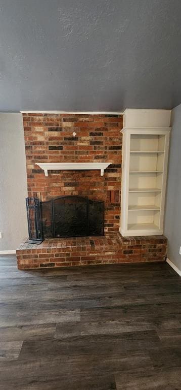 room details featuring a brick fireplace, a textured ceiling, hardwood / wood-style flooring, and built in features