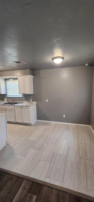 kitchen with white cabinetry, sink, and a textured ceiling