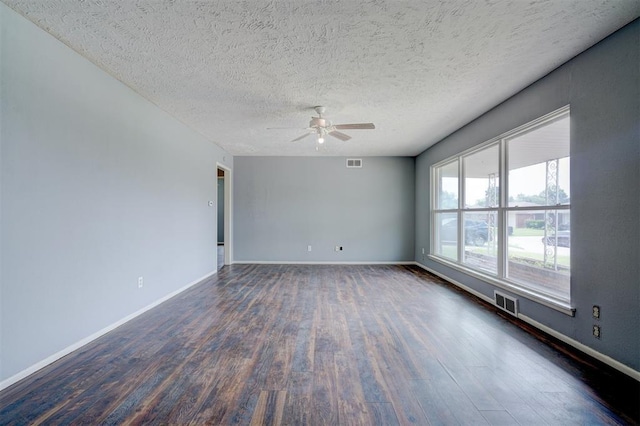 empty room featuring ceiling fan, a textured ceiling, and dark wood-type flooring