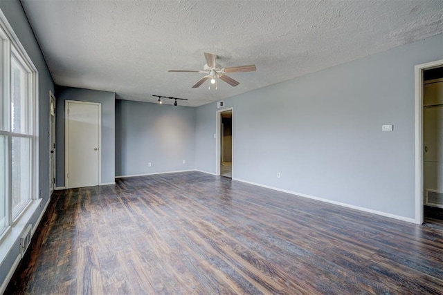 spare room featuring a wealth of natural light, dark hardwood / wood-style flooring, rail lighting, and a textured ceiling