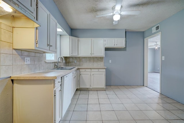 kitchen with backsplash, sink, light tile patterned floors, a textured ceiling, and white cabinetry