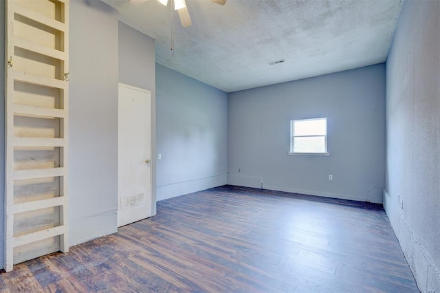 empty room featuring dark hardwood / wood-style flooring, ceiling fan, built in features, and a textured ceiling