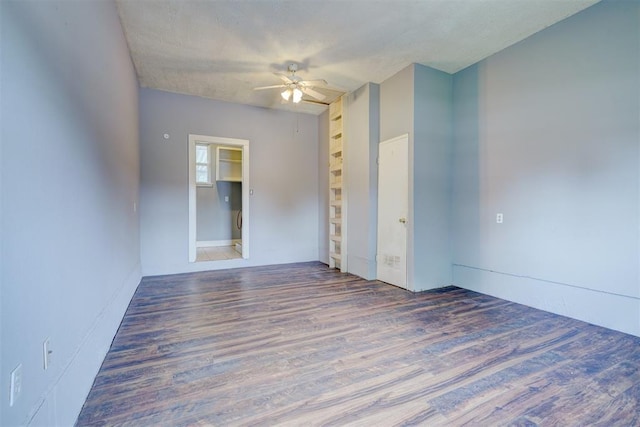 empty room featuring a textured ceiling, ceiling fan, and dark wood-type flooring