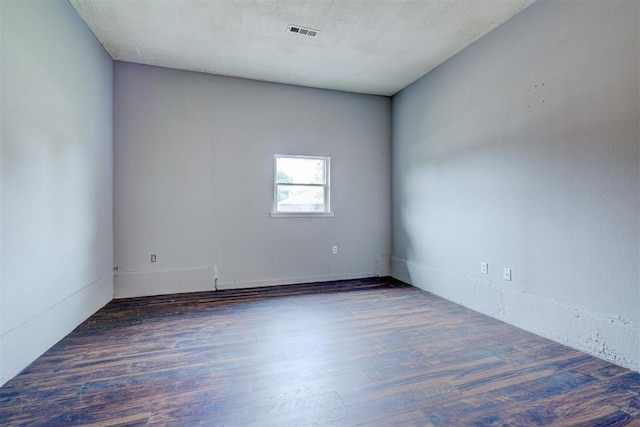 spare room featuring a textured ceiling and dark wood-type flooring