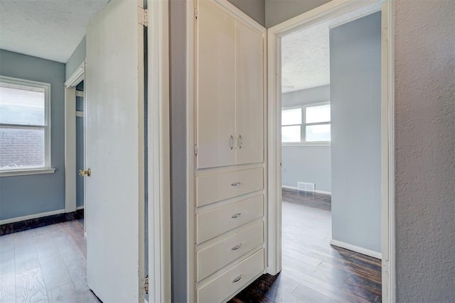 hall featuring a textured ceiling and dark wood-type flooring