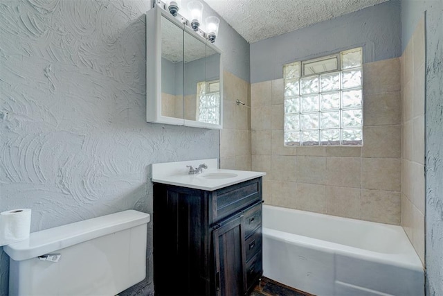 full bathroom with a textured ceiling, vanity, toilet, and tiled shower / bath