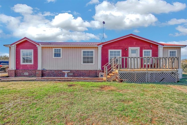 rear view of property featuring a wooden deck and a lawn