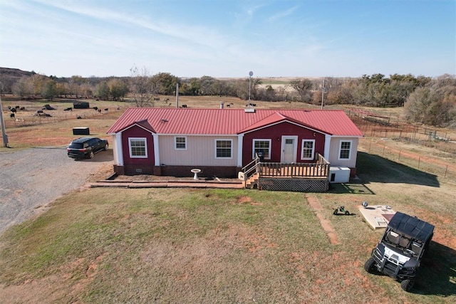 view of front of property with a wooden deck, a front yard, and a rural view