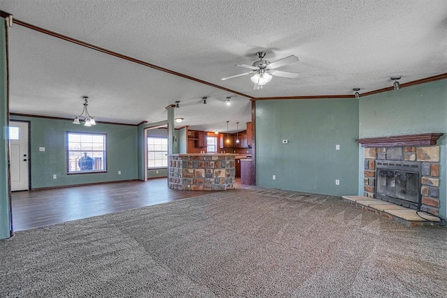 unfurnished living room with crown molding, a stone fireplace, and dark colored carpet