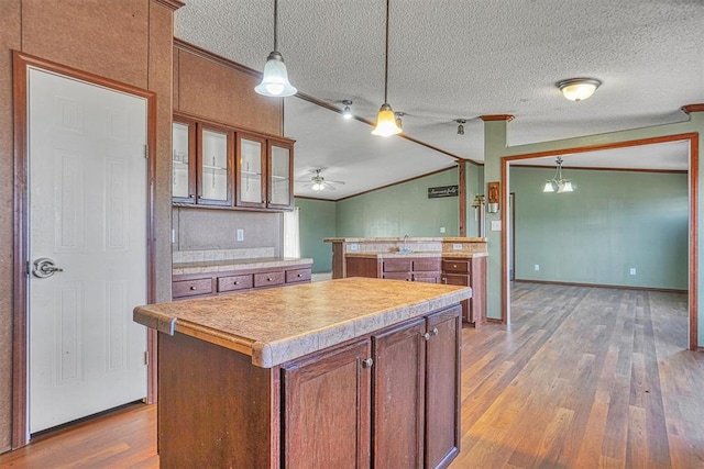 kitchen with wood-type flooring, lofted ceiling, a center island, and ornamental molding