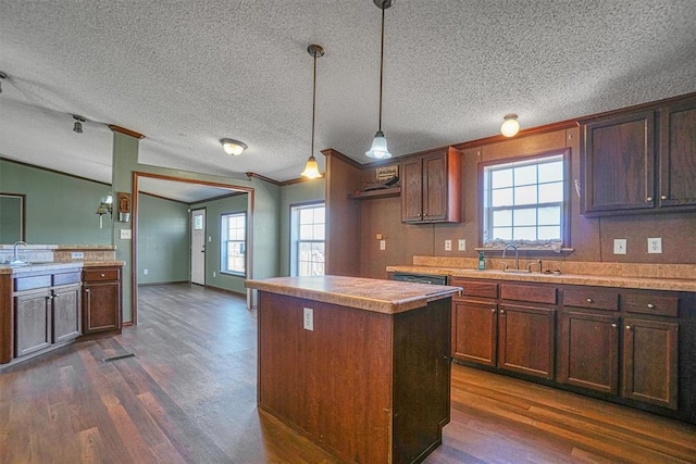 kitchen featuring a kitchen island, sink, hanging light fixtures, crown molding, and dark wood-type flooring