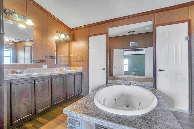 bathroom featuring crown molding, hardwood / wood-style floors, vanity, a bath, and a textured ceiling