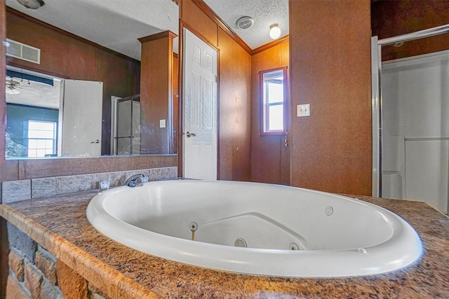 bathroom with a bathtub, crown molding, a wealth of natural light, and a textured ceiling