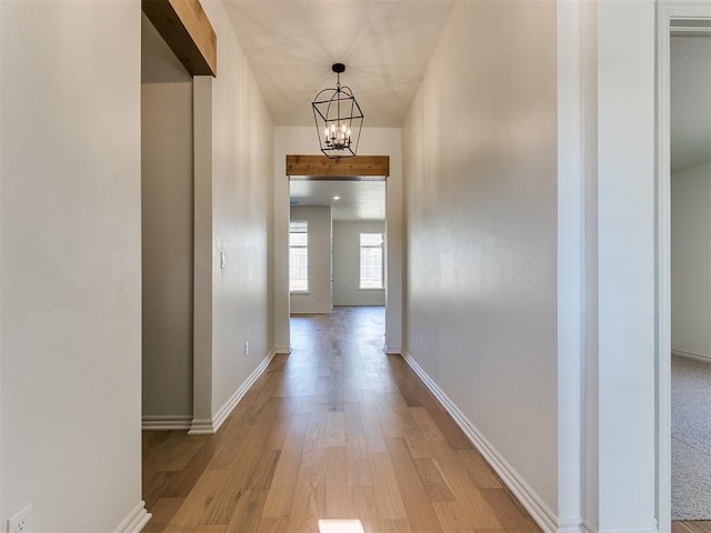 corridor featuring a notable chandelier and light wood-type flooring