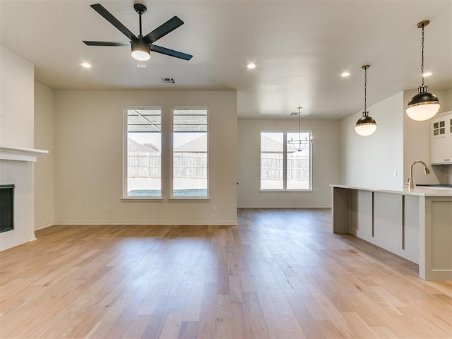 unfurnished living room featuring ceiling fan, sink, and light hardwood / wood-style floors